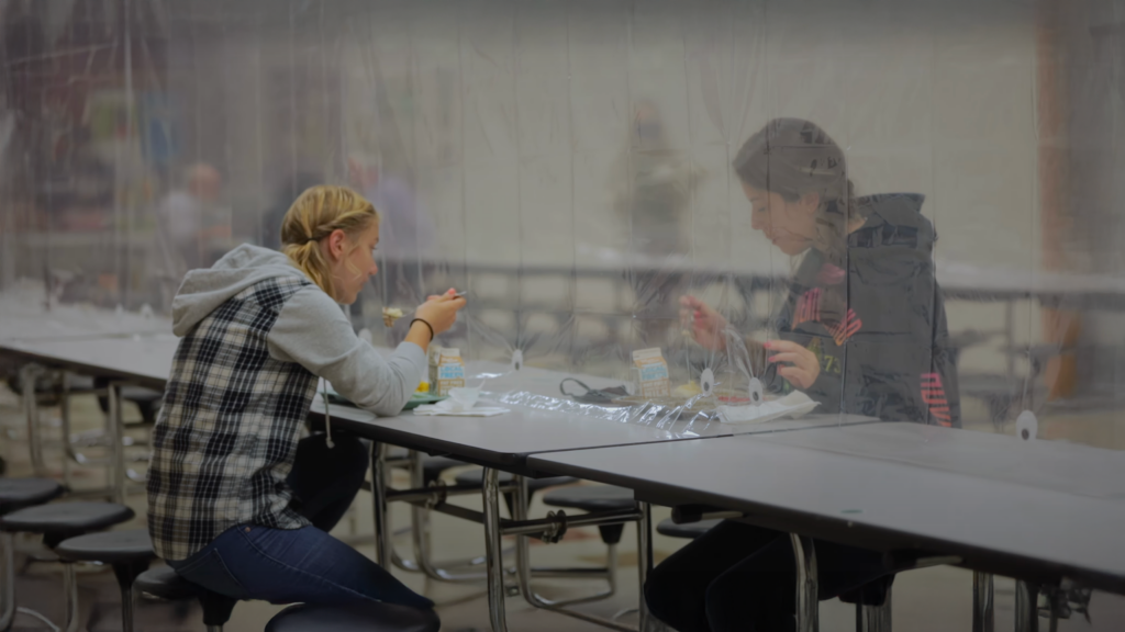 Students eating lunch with a plastic barrier.